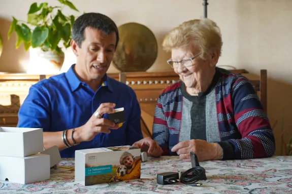 facteur expliquant à une personne âgée l'utilisation d'un bracelet connecté de santé